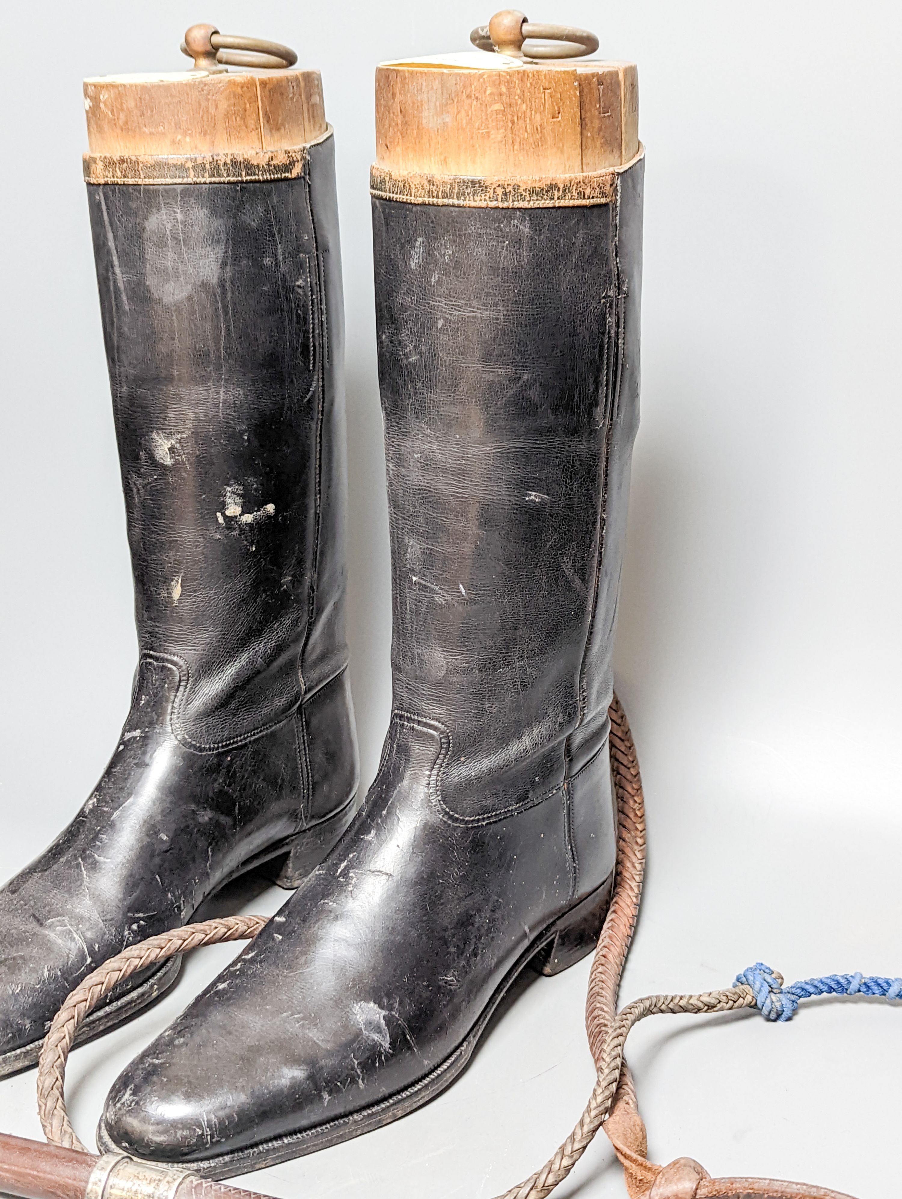 A pair of black leather riding boots with trees, a silver mounted whip and spurs